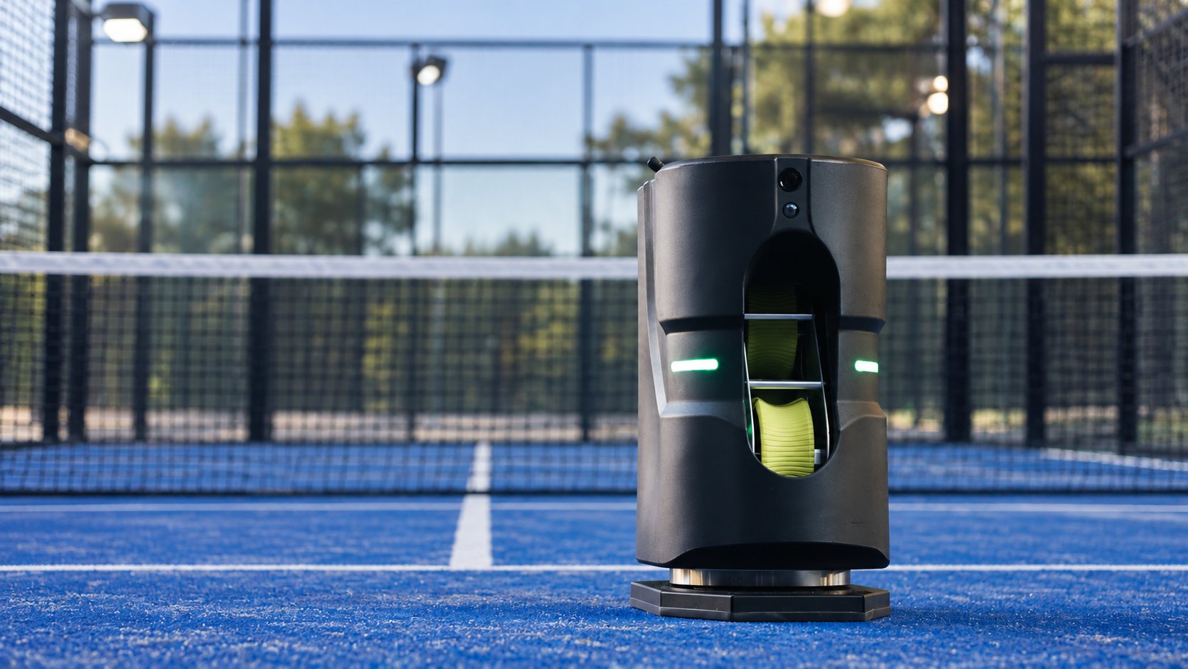 Tennibot Partner Lite padel ball machine on an outdoor blue padel court, with the net and glass enclosure behind it
