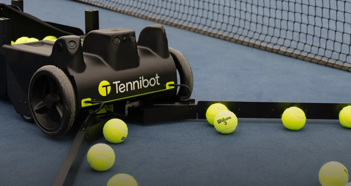 A Tennibot Rover collecting tennis balls from a hard court
